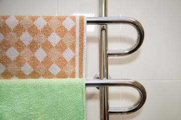 Modern bathroom with towel warmer with green and brown towel