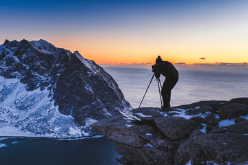 Silhouette of Landscape Photographer on sunset on mountain summit in Lofoten Islands Archipelago in Norway, Scandinavia, Europe.