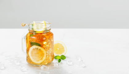 Iced tea with lemon slices and mint on light gray stone background.