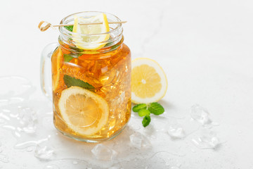 Iced tea with lemon slices and mint on light gray stone background.