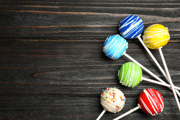 Bright delicious cake pops on wooden table, flat lay. Space for text