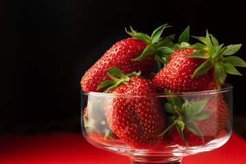 Closeup Strawberries in a glass dish on a red and black background