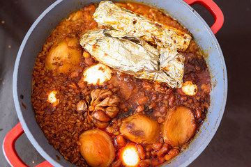 Hot plate for the Sabbath, a pot of spicy meat cooked with potatoes, barleys, wheat and eggs. Pot of cholent Hamin in hebrew, challah-special bread in Jewish cuisine. Traditional food Jewish Shabbat.