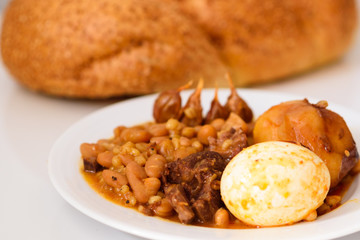 Challah Shabbat bread and hamin or cholent in hebrew - Sabbath traditional food on white table in the kitchen.