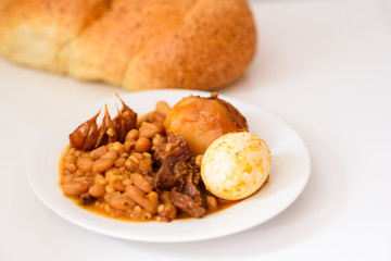 Challah Shabbat bread and hamin or cholent in hebrew - Sabbath traditional food on white table in the kitchen.