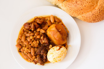 Challah Shabbat bread and hamin or cholent in hebrew - Sabbath traditional food on white table in the kitchen.