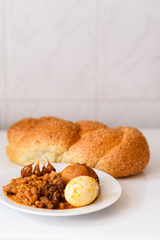 Challah Shabbat bread and hamin or cholent in hebrew - Sabbath traditional food on white table in the kitchen.