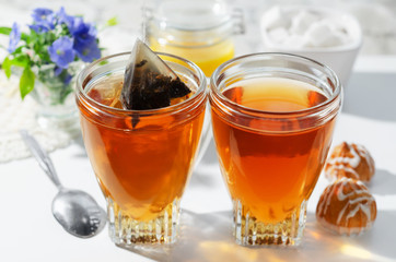 Two cups of hot tea bags, cookies and honey. Flowers in the background.The process of brewing tea....