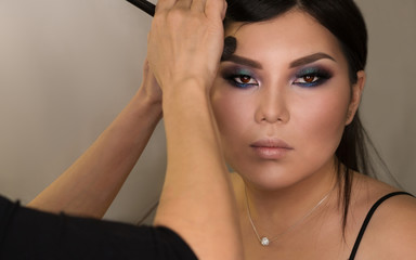Naklejka premium Makeup artist working with Asian model in beauty salon. Face sculpt. Contouring. Make up woman face. Contour and highlight. Beauty industry. Space for text