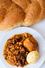 Challah Shabbat bread and hamin or cholent in hebrew - Sabbath traditional food on white table in the kitchen.