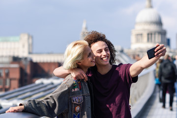 Happy couple taking a selfie photograph on London's Millennium Bridge
