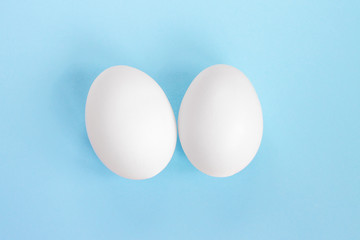 Two white eggs on a blue background. Creative concept in the style of minimalism. The birth of twin boys concept