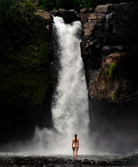 young woman backpacker looking at the waterfall in jungles