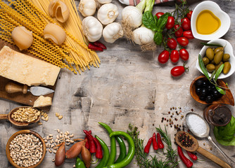 top view, on a dark rustic background, raw pasta and traditional Italian ingredients with olive oil, parmesan, vegetables, legumes and various types of spices