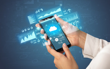 Female hand using smartphone with financial tracking concept illustrated by graphs and symbols