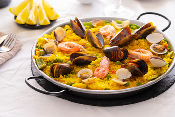 Seafood Paella with  prawns, clams and mussels on saffron rice with vegetables served in  traditional frying pan. Paella de marisco Spanish cuisine background. Copy space.