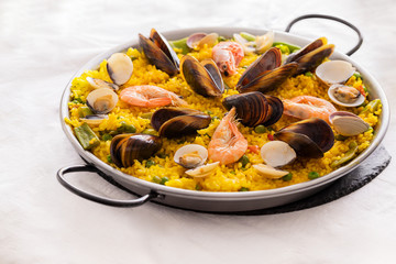 Seafood Paella with  prawns, clams and mussels on saffron rice with vegetables served in  traditional frying pan. Paella de marisco   Spanish cuisine background.