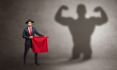 Businessman standing with red cloth on his hand and strong hero shadow on the background

