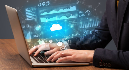 Businessman hand typing on laptop with reports and graphs concept around
