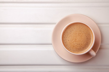Cup of coffee with foam on white table. Top view
