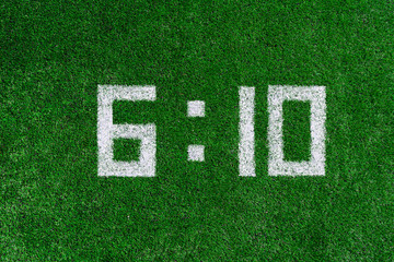 Football score 6:10.White numbers six and ten are drawn on the green grass,creative scoreboard