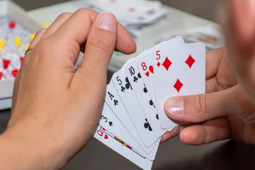Family fun card sequence game showing a hand or cards looking over shoulder of a mom playing with her kids.