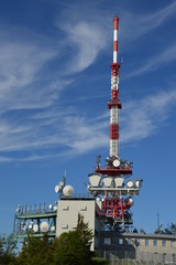 Fernsehantenne und Mobilfunkmast vor blauem Himmel