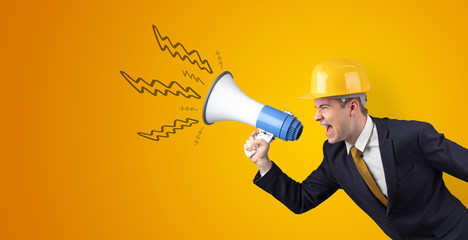 Fototapeta premium Young architect constructor yelling with megaphone and copyspace