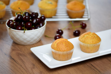 Delicious organic muffins. Vanilla muffins with cherry on a white plate.