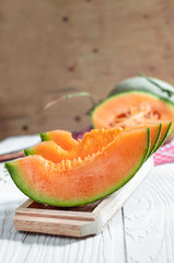 Fresh of whole and sliced orange melon or cantaloupe on tray board and background wooden table. Favorite fruit in summer concept.