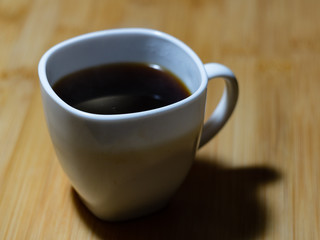 White mug with black coffee on a wooden table
