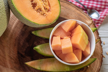 Fresh of whole orange melon or cantaloupe and cut intp pieces on background wooden table. Favorite fruit in summer concept.