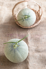 Fresh of whole orange melon or cantaloupe on burlap fabric sack background and wooden table....