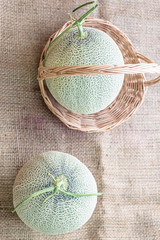 Fresh of whole orange melon or cantaloupe on burlap fabric sack background and wooden table....