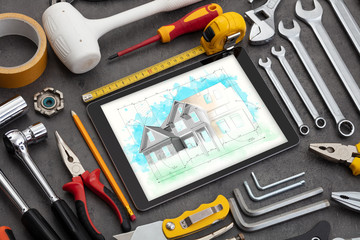 Tablet with construction tools and house plan concept

