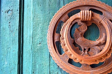 part of unusual round rusted door handle with a bird-like element