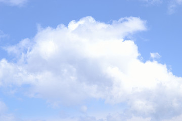 Naklejka na ściany i meble A big white cloud in the blue sky. Background. Disheveled cheerful Cumulus cloud.