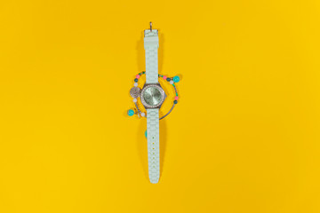 A white watch is laying in the middle of a bracelet on a white surface