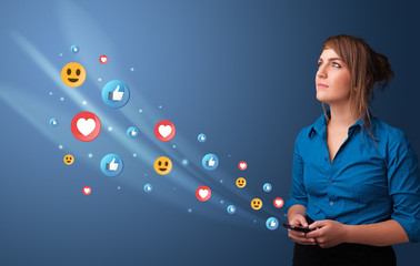 Young person using smartphone with flying social media icons around
