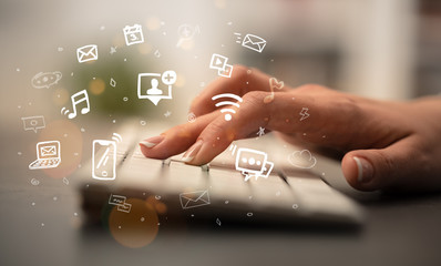 Business woman hand typing on keyboard with drawn application icons around
