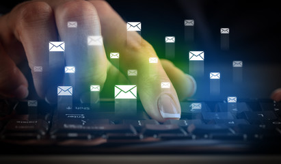 Business woman typing on keyboard with mail icons around
