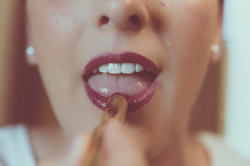 Naklejka premium woman painting her lips with carmine