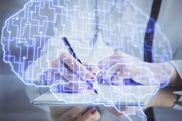 Multi exposure of woman's writing hand on background with brain hud. Concept of learning.