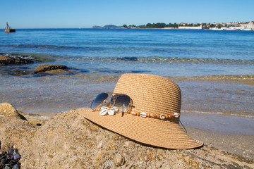 hat and sunglasses. Beach accessories for sun protection on white sand, blue sky and sea...