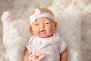 Fototapeta na wymiar Cute Baby Doll in white pale clothes isolated on beige background.