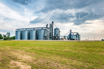 Fototapeta na wymiar agro-processing plant for processing and silos for drying cleaning and storage of agricultural products, flour, cereals and grain with beautiful clouds