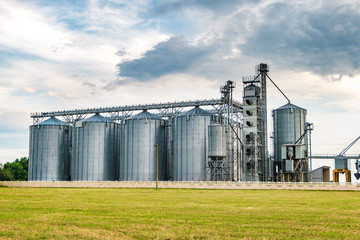 Obraz premium agro-processing plant for processing and silos for drying cleaning and storage of agricultural products, flour, cereals and grain with beautiful clouds