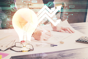 View of Bulb lamp idea concept icon on a futuristic interface with writing man's hand background. Double exposure.