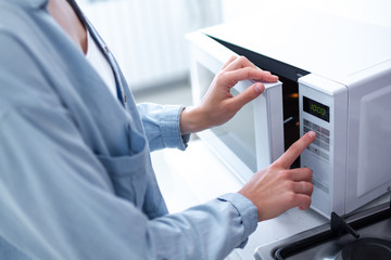 Woman using the microwave oven to heating food at kitchen at home 