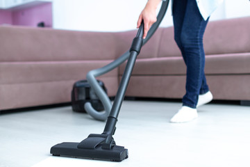 Fototapeta na wymiar Housewife vacuuming apartment with using vacuum